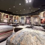 Rug Gallery, large rugs hang on the walls and piles of different size rugs fill the center of this large room, an old movie theatre, refurbished into modern day gallery.